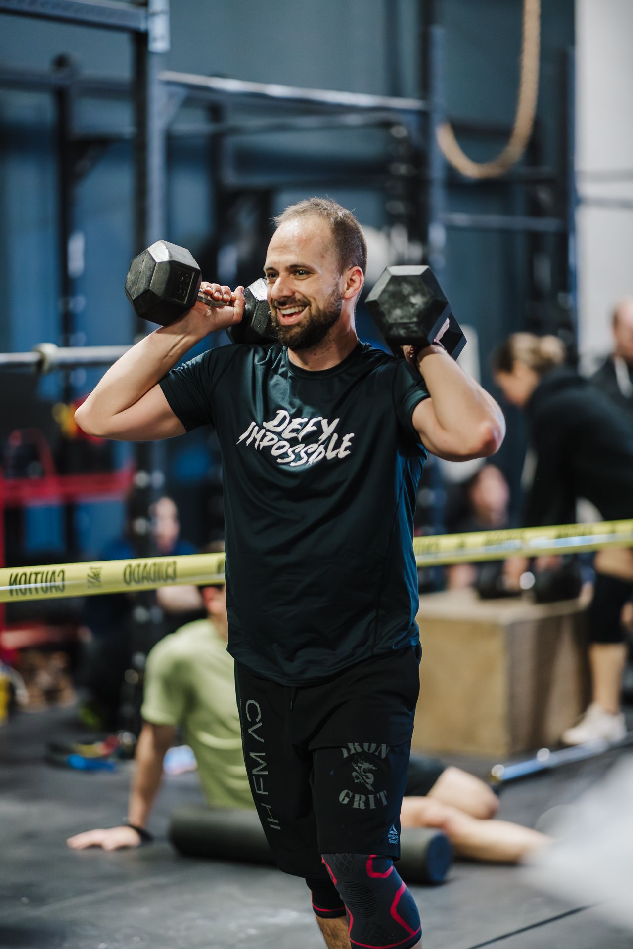 Smiling Boston Iron Grit member carrying dumbbells during a partner workout